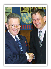 Dr. Pál L. Bölcskei erhält Bundesverdienstkreuz Zwei ältere Herren in Anzug mit Brille schütteln sich lächelnd die Hände.