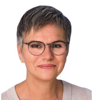 Martina Jonas Porträt vor weißem Hintergrund, von einer Frau mit kurzen grauen Haaren, dunkler Brille und beigem Pullover, die in die Kamera lächelt.