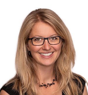 Hannah Krause Porträt vor weißem Hintergrund: von einer Frau mit langen blonden Haaren, schwarzem T-Shirt und dunkler Brille, die in die Kamera lächelt.